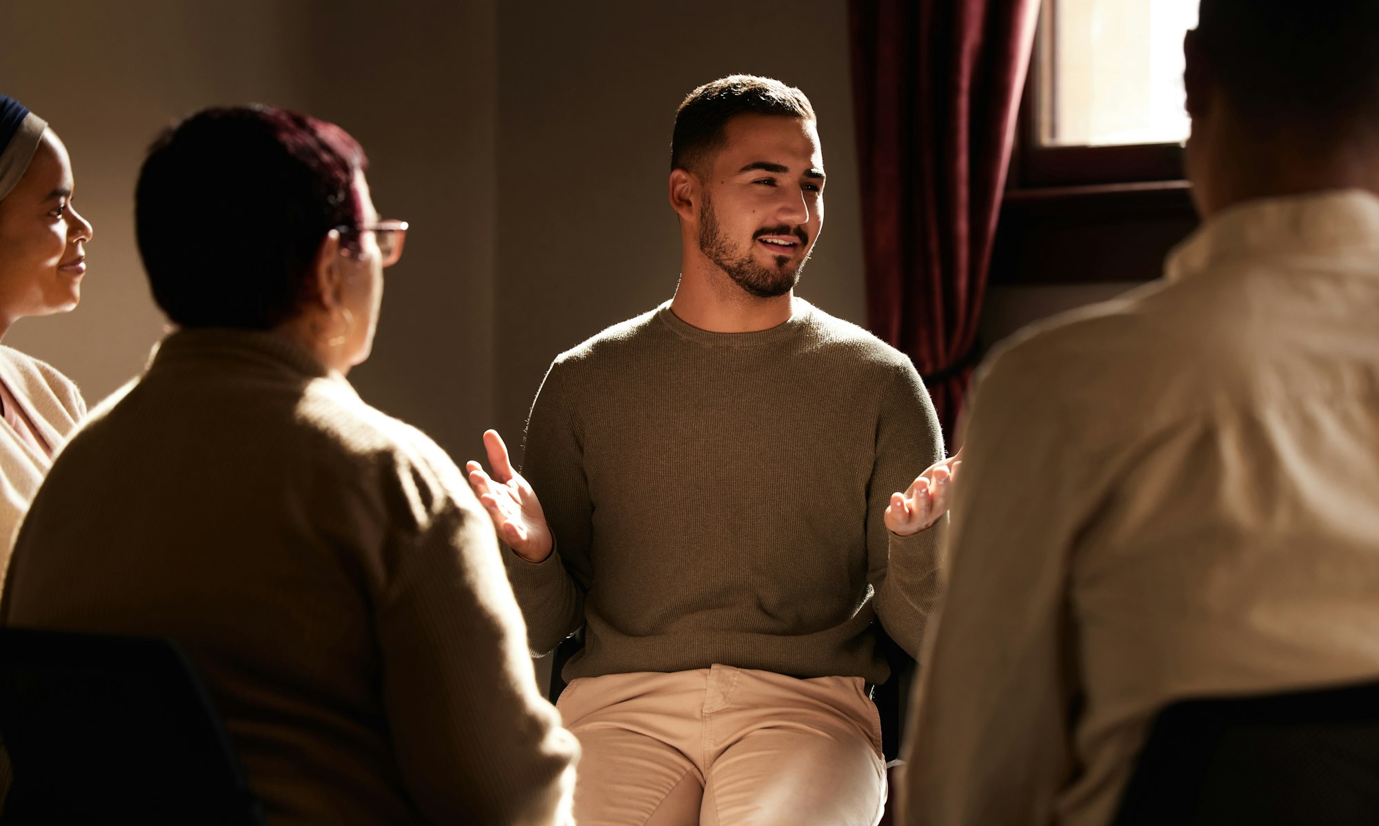 Support, smile and man sharing in group therapy with understanding, feelings and talking in session